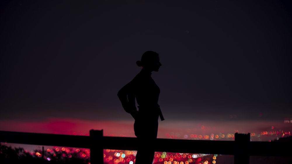 silhouette of man standing on bridge during night time