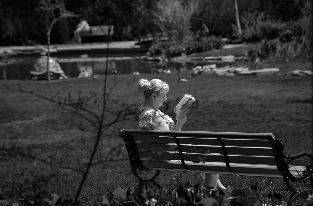 girl sitting on bench in grayscale photography