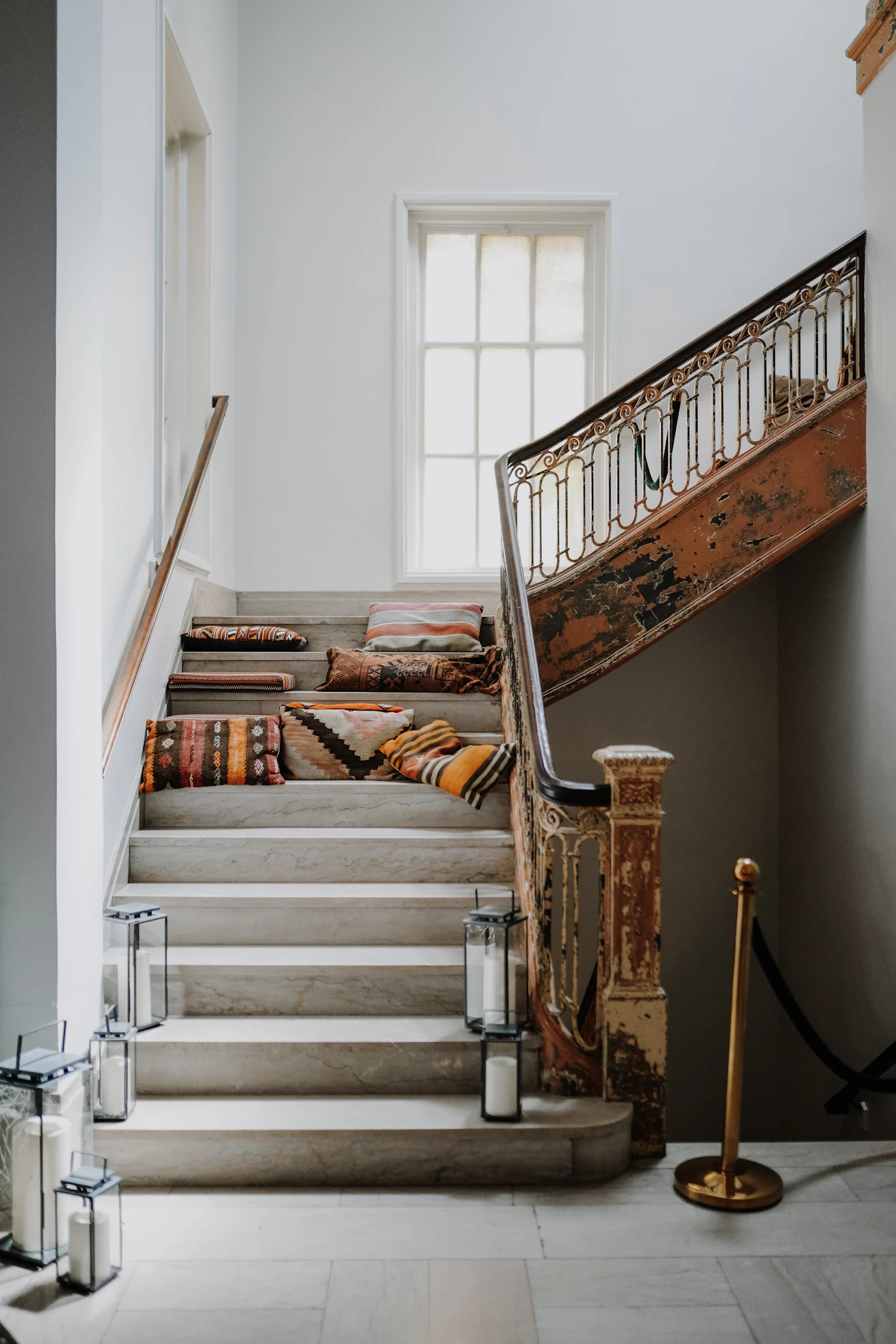 A warm staircase with dark wood, stone steps, and patterned cushions.