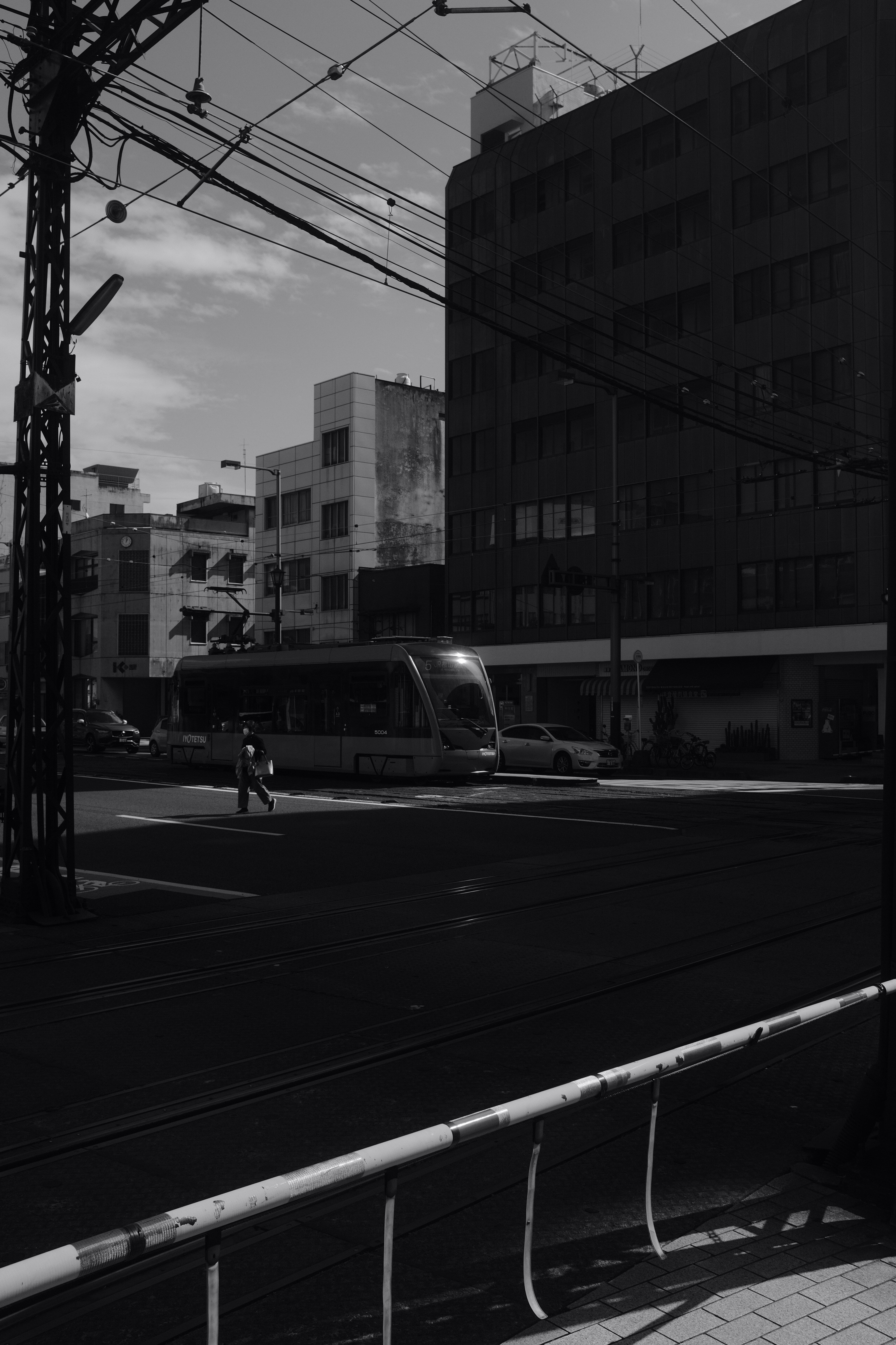 grayscale photo of man walking on sidewalk near building