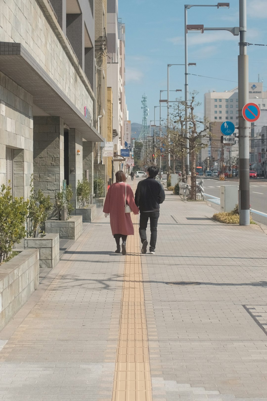 woman in red coat walking on sidewalk during daytime