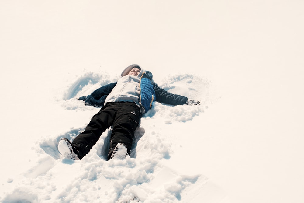 person in black pants lying on snow covered ground during daytime