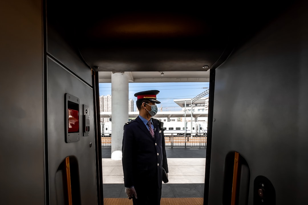 man in black suit standing near train