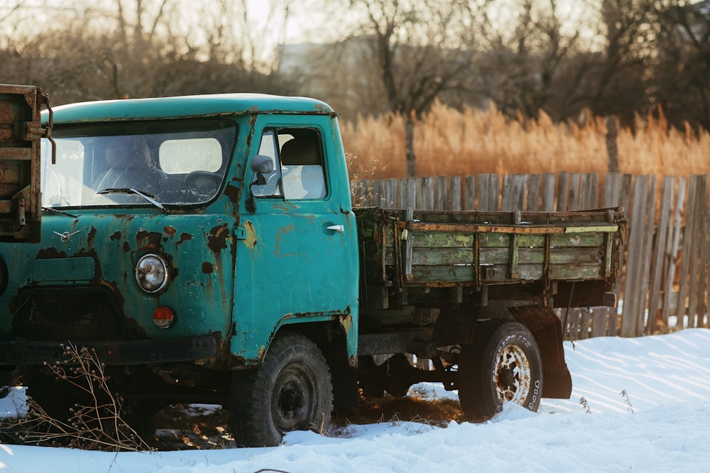 green and brown truck on snow covered ground during daytime