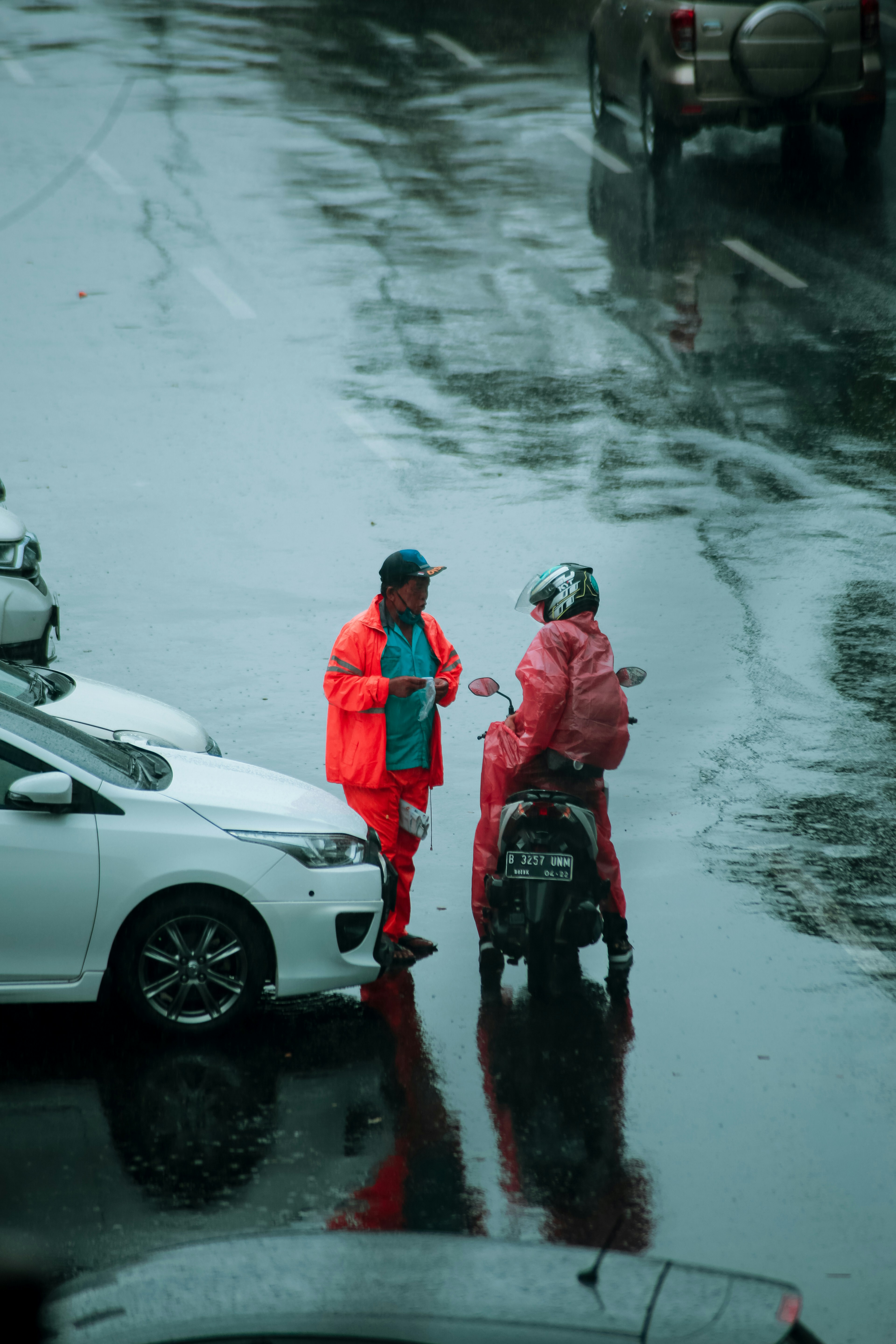 2 men in white jacket and helmet standing beside white car during daytime