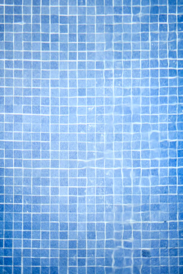 Close-up of freshly installed blue mosaic tiles shimmering under soft lighting in a modern kitchen.