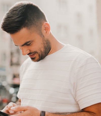 man in white crew neck t-shirt using smartphone