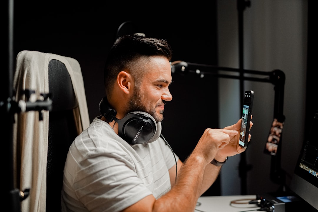 Man recording an instagram story with headphones in front of a smartphone with podcast gear like headphones, an interface and a microphone stand. It's a very clear content marketing image