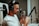 A person wearing headphones is speaking into a professional studio microphone, which is mounted on an adjustable arm. The individual appears focused and engaged with the recording process.