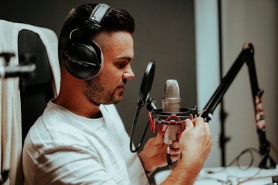 An African man with headphones and a microphone in a warm studio setting reflecting audio production energy.