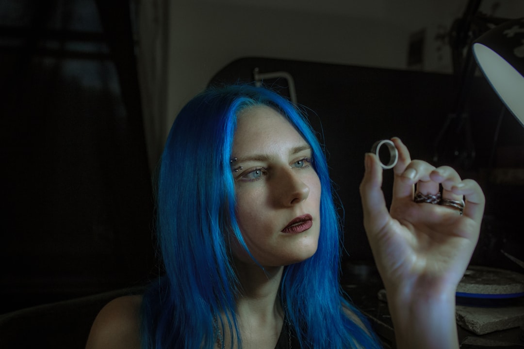 woman with blue hair holding white round ornament