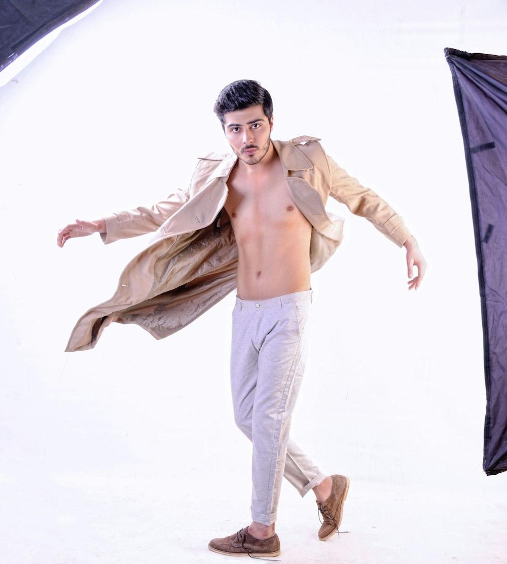 topless man in white pants holding black textile