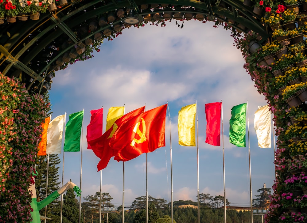 red white and green flags on black metal pole under white clouds and blue sky during