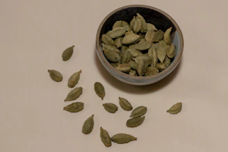 Close-up of vibrant green cardamom pods arranged neatly on a rustic wooden surface.