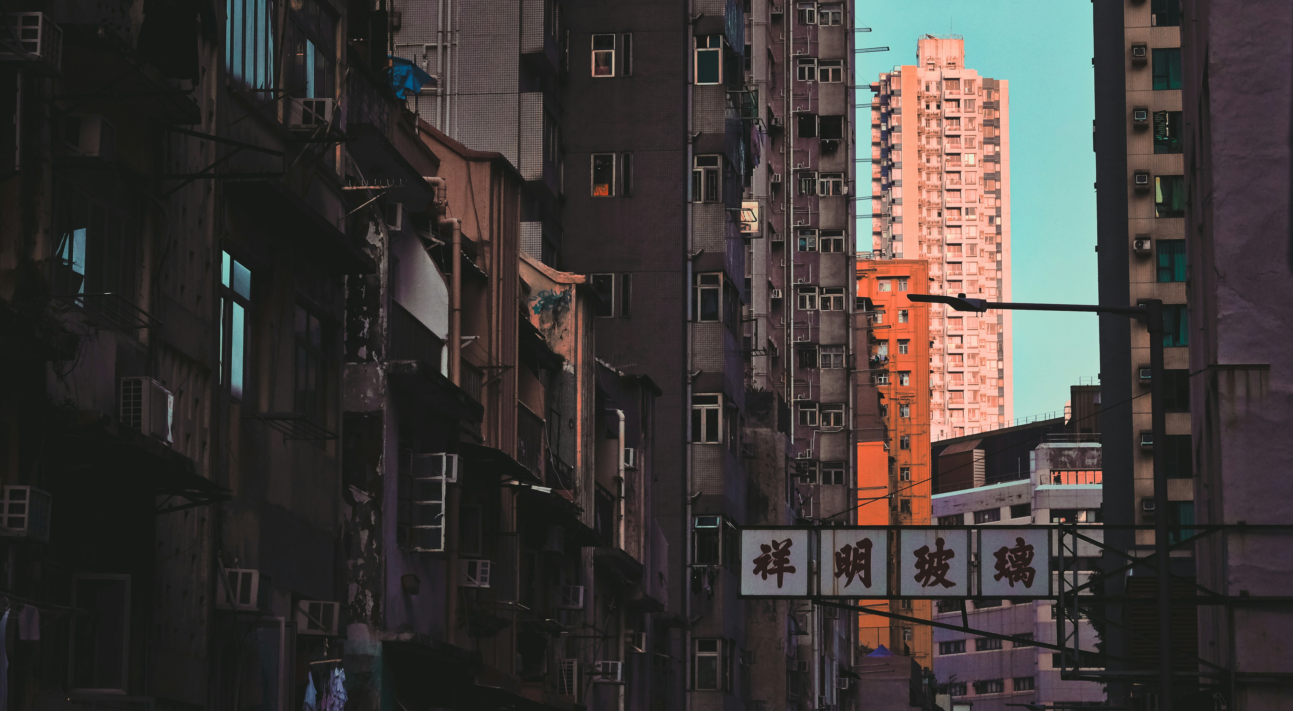 cars parked on side of the road in between high rise buildings during daytime