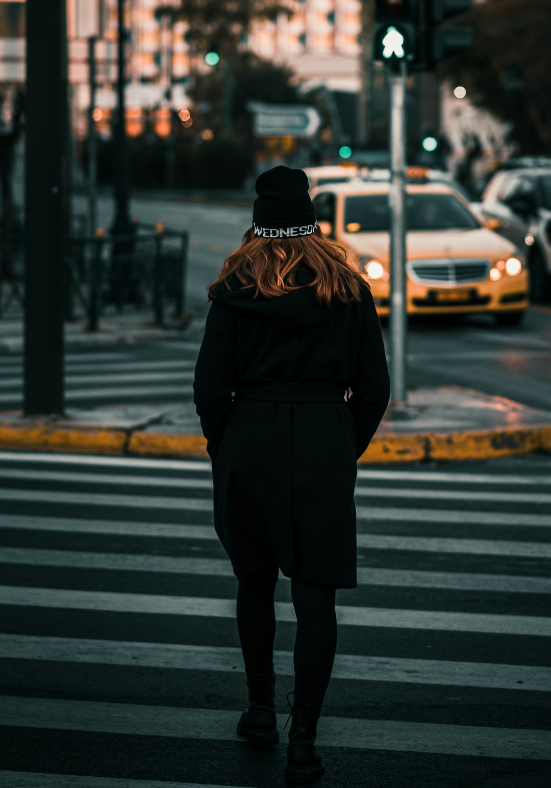 person in black coat and brown knit cap standing on pedestrian lane during daytime