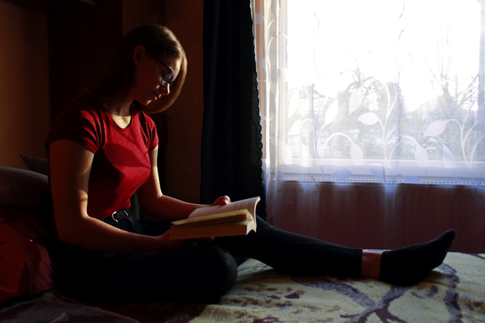 Mujer con camiseta sin mangas roja leyendo libro