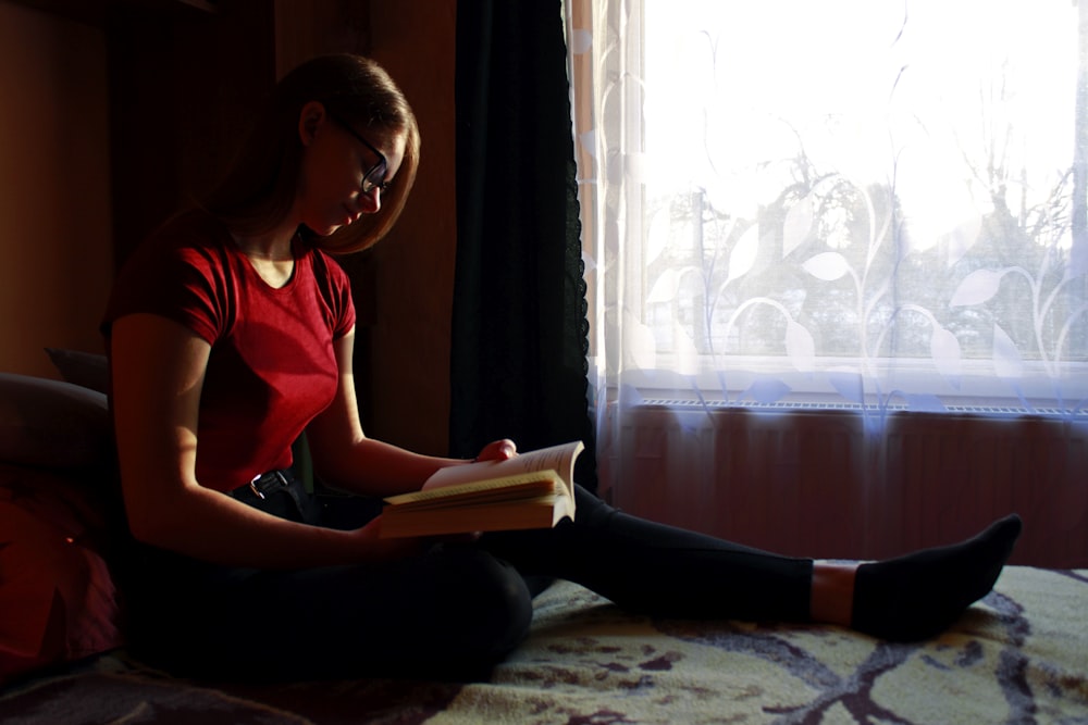 woman in red tank top reading book