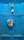 A bright blue wooden door is adorned with a colorful painter's palette and a decorative hanging, which includes a small bell and beads.