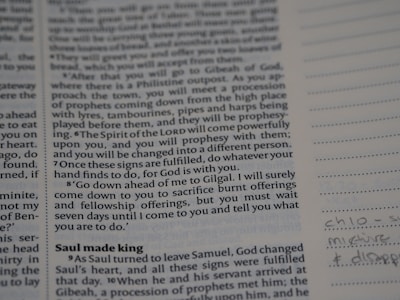 A close-up of an open Quran with digital notes beside it on a tablet.