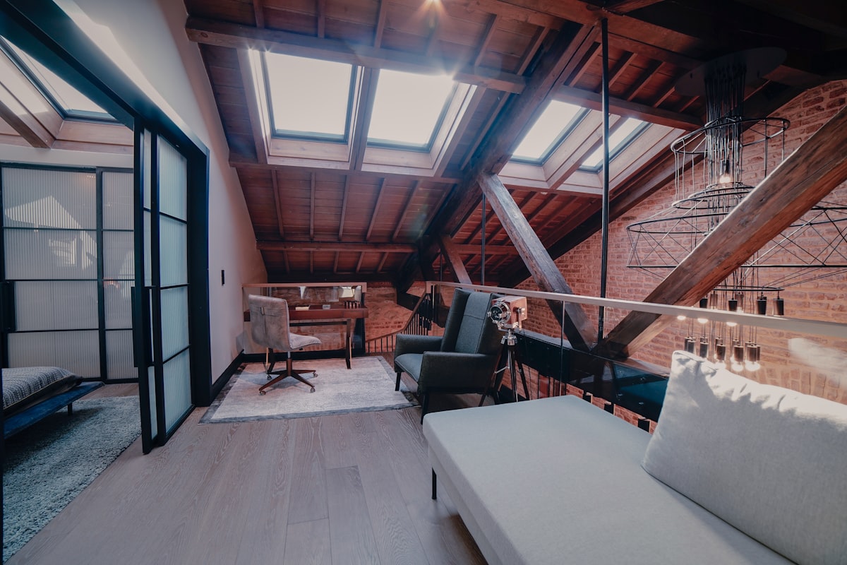 Bright converted loft living space with a bank of VELUX roof windows in the sloped ceiling and exposed timber beams