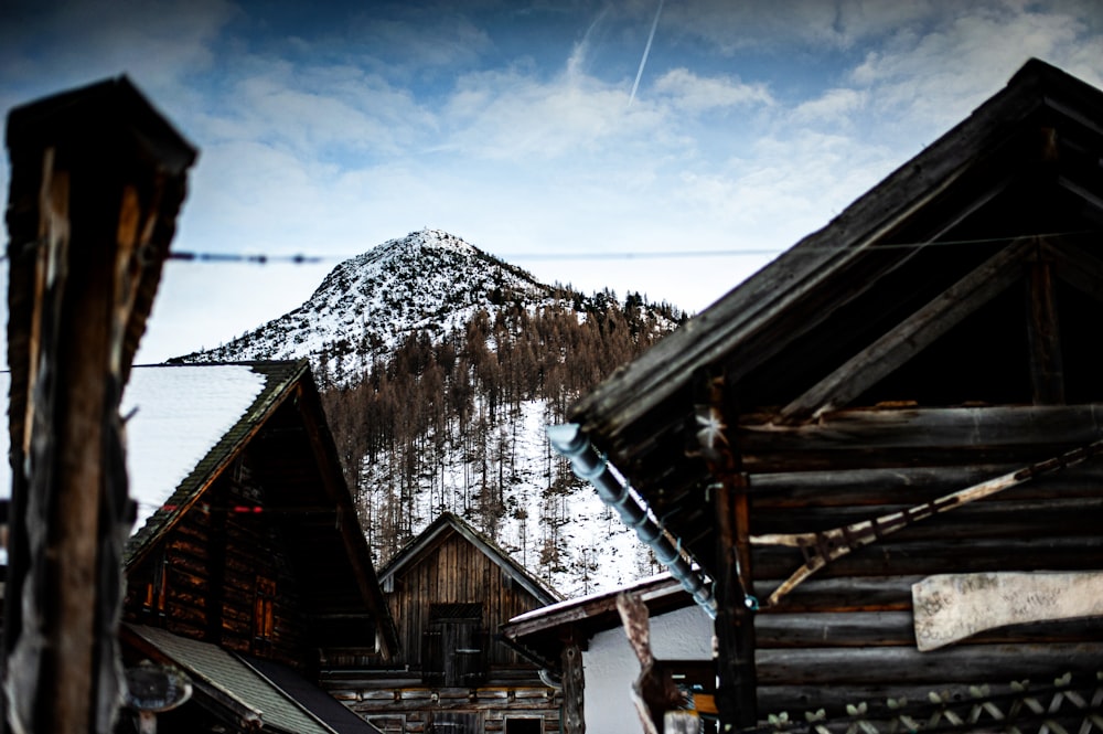 brown wooden house near snow covered mountain during daytime