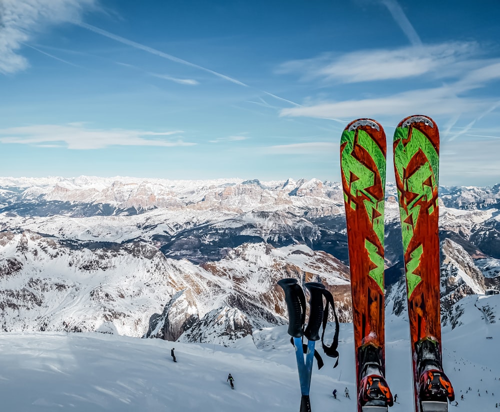 검은 바지와 파란 눈 스키 블레이드를 입은 사람이 낮에 눈 덮인 산에 서 있다