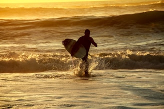 man in black wetsuit surfing on sea waves during sunset