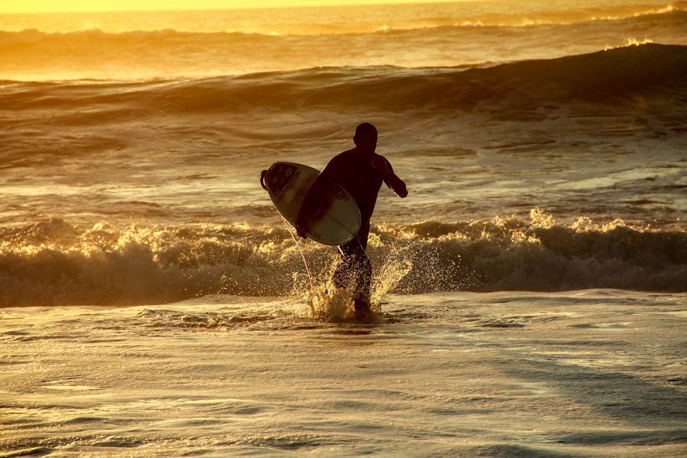 man in black wetsuit surfing on sea waves during sunset