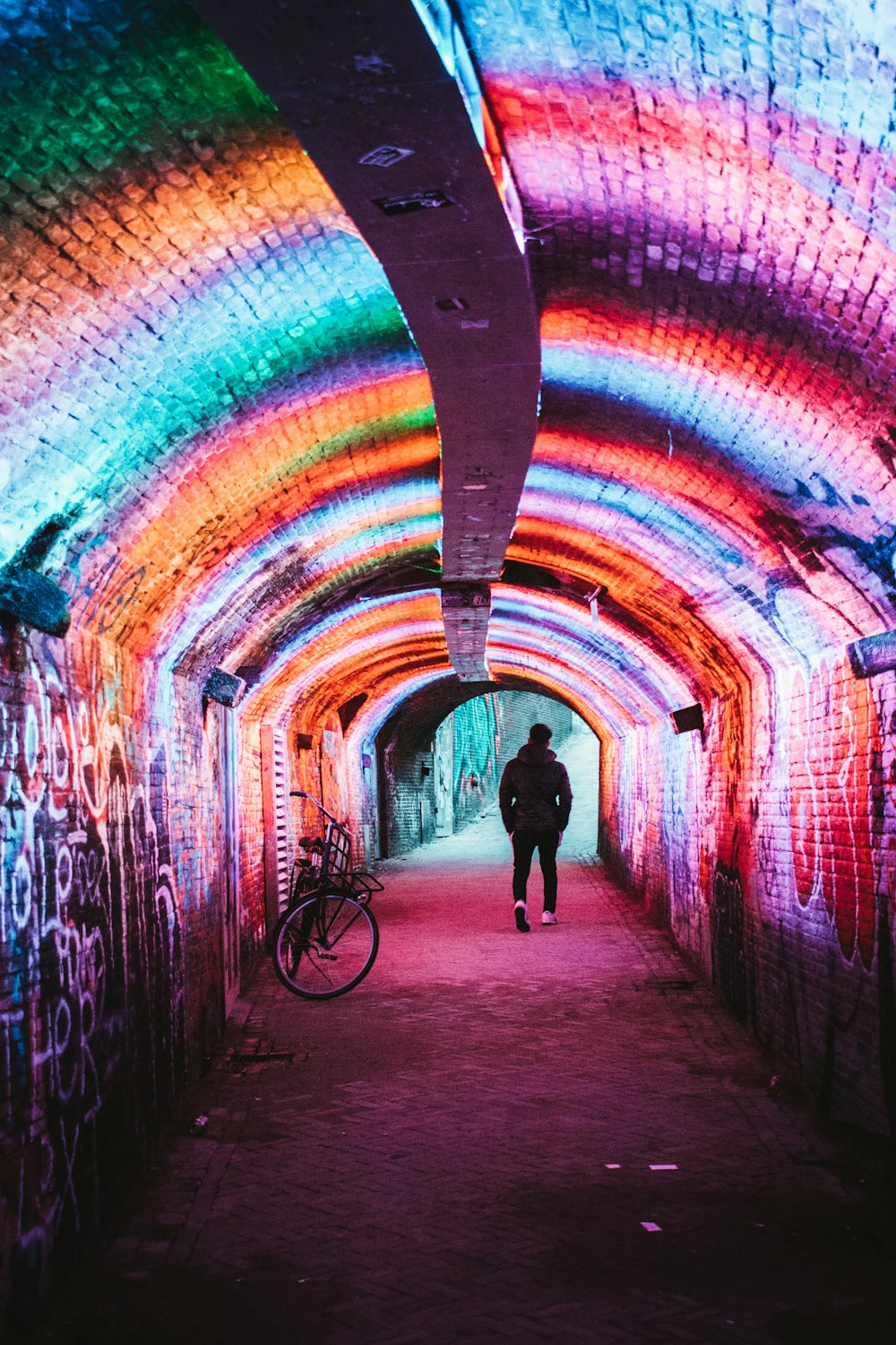 man in black jacket walking on tunnel