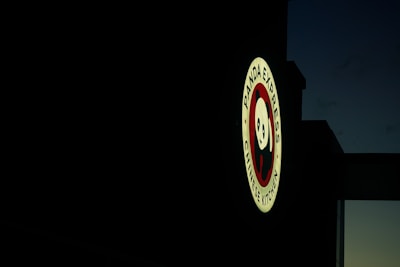 A brightly lit sign featuring the Panda Express logo, with a cartoon panda face and the text 'Panda Express Chinese Kitchen', set against a dark, evening sky.