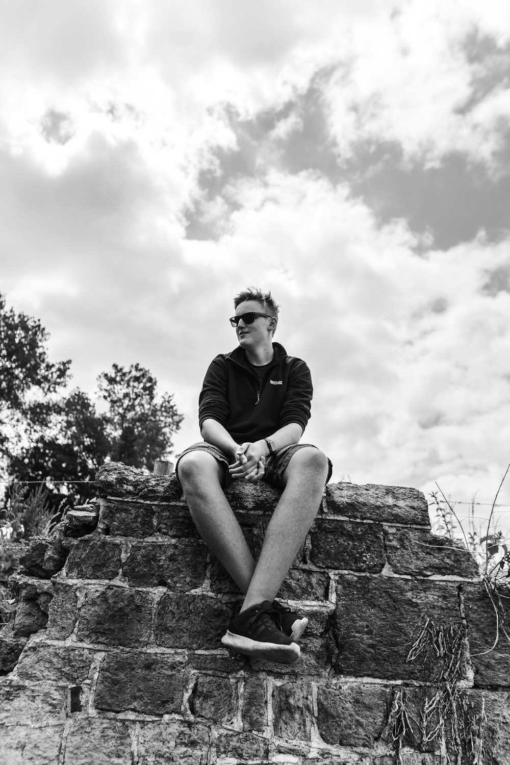 man in black t-shirt sitting on rock