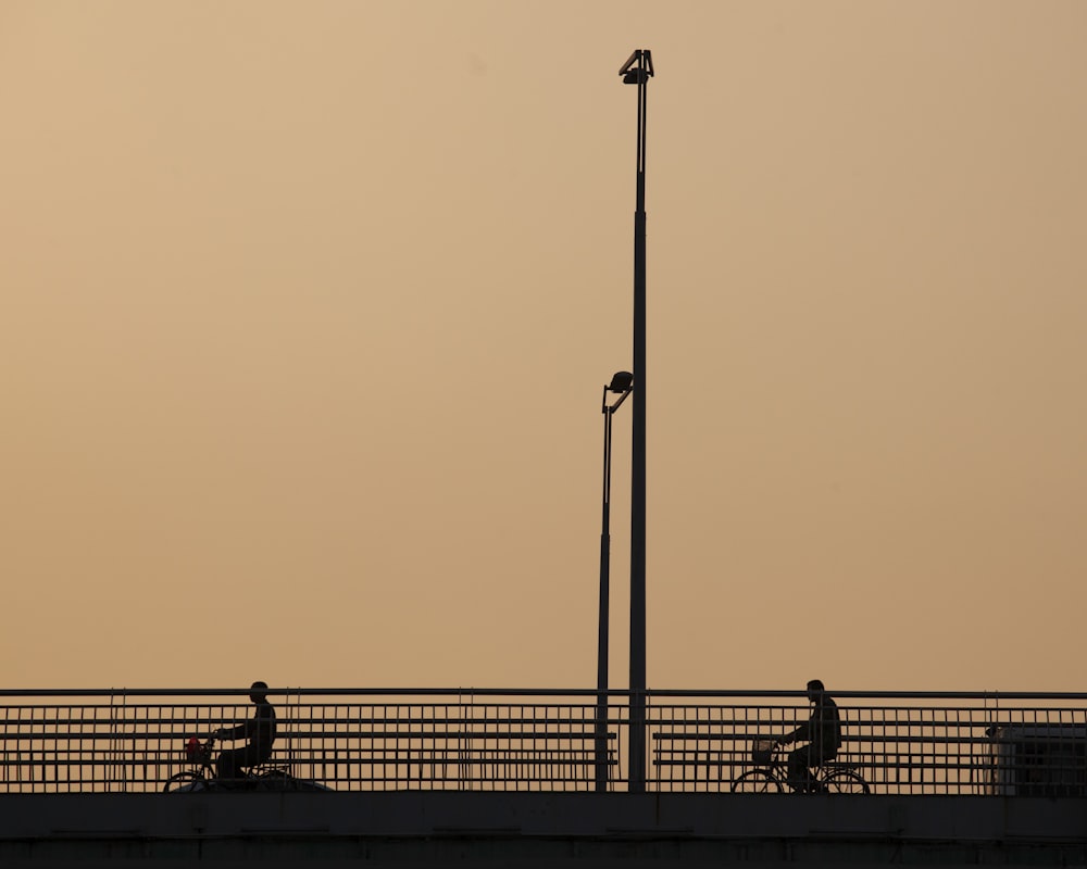 silhouette of people standing on dock during sunset