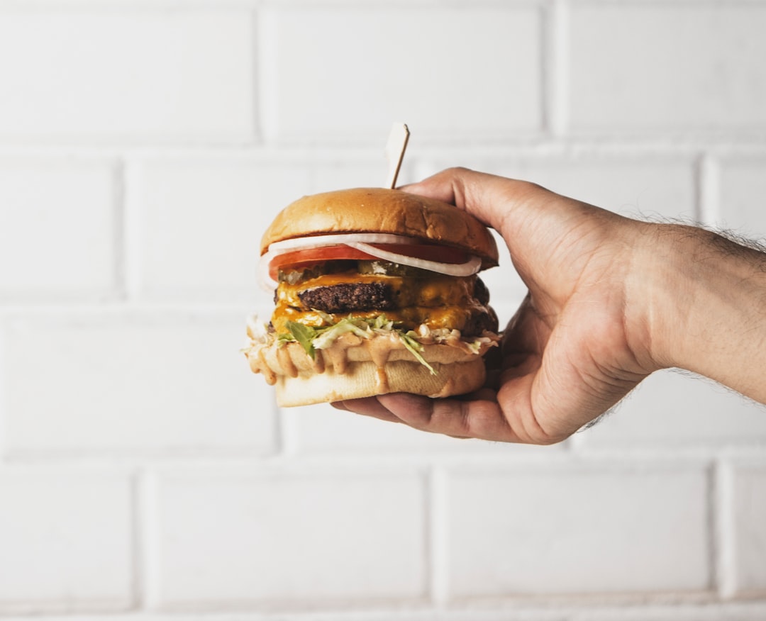 person holding burger with patty and lettuce