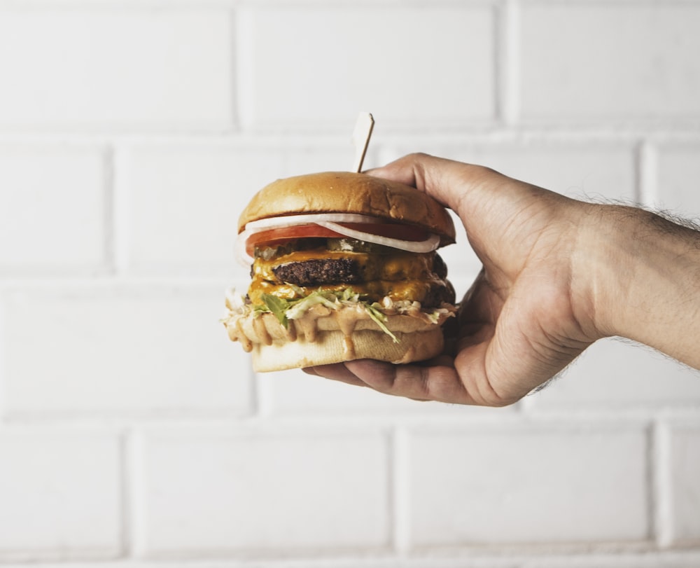 person holding burger with patty and lettuce