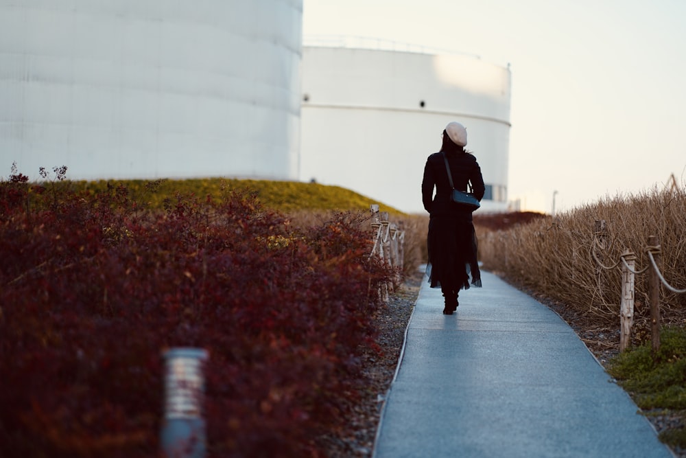 woman in black coat walking on pathway