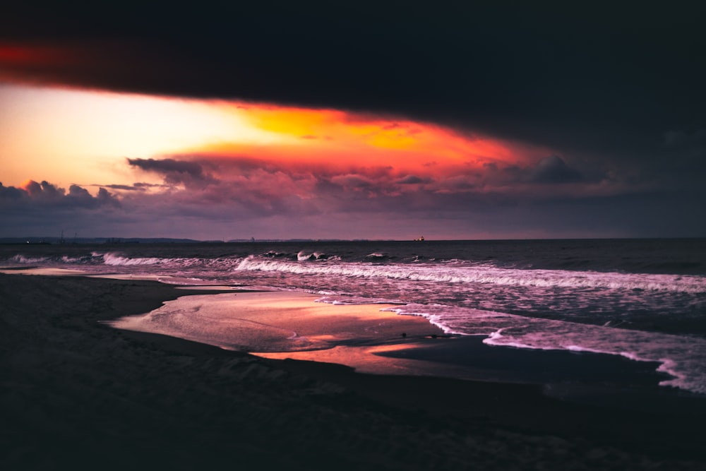 sea waves crashing on shore during sunset