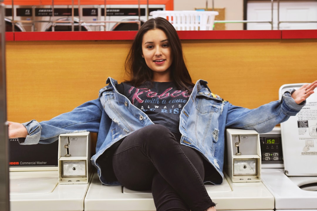 woman in blue denim jacket and black pants sitting on white table