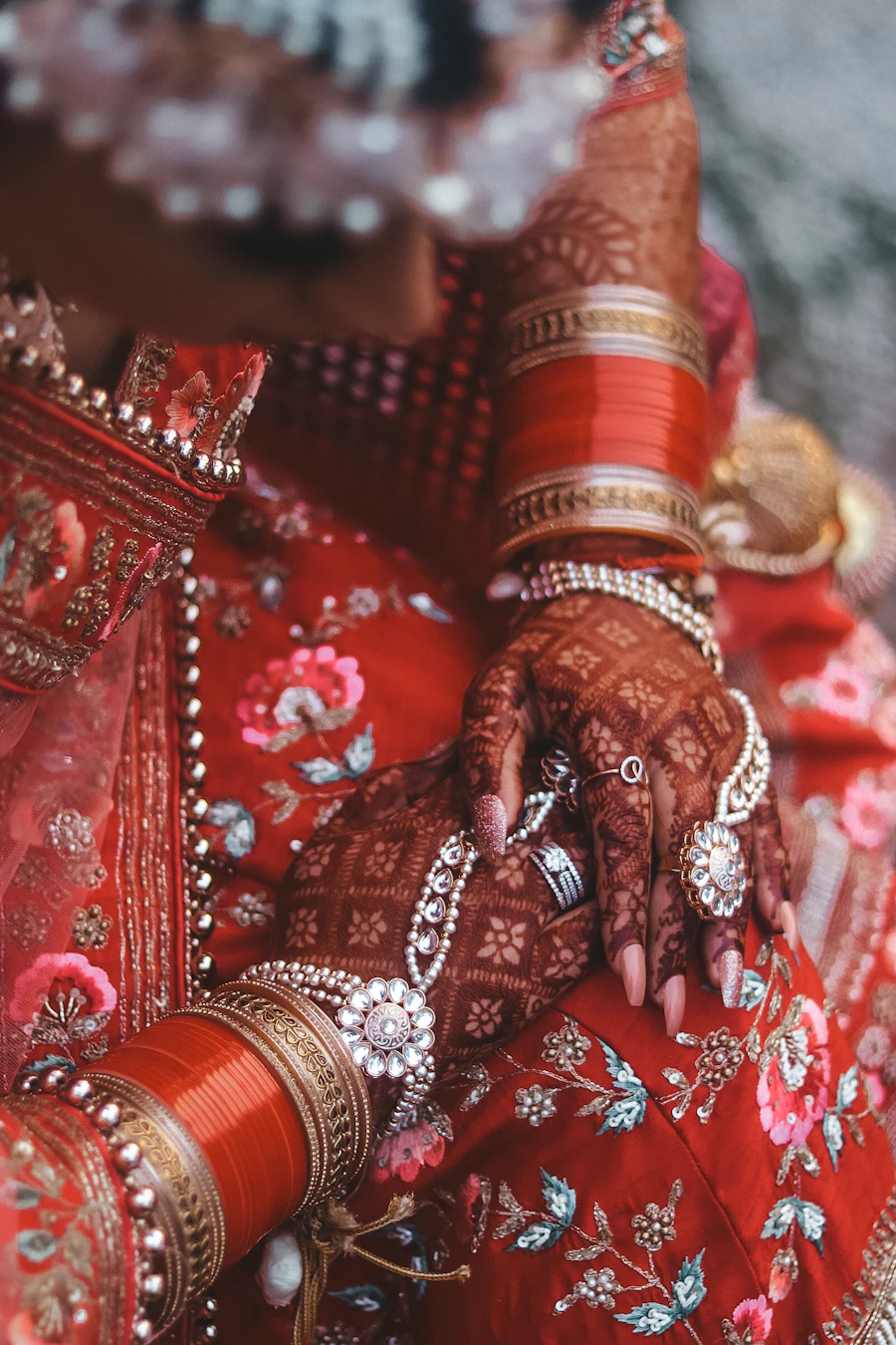 Bride's hands wearing a traditional red and ivory Punjabi chooda with henna