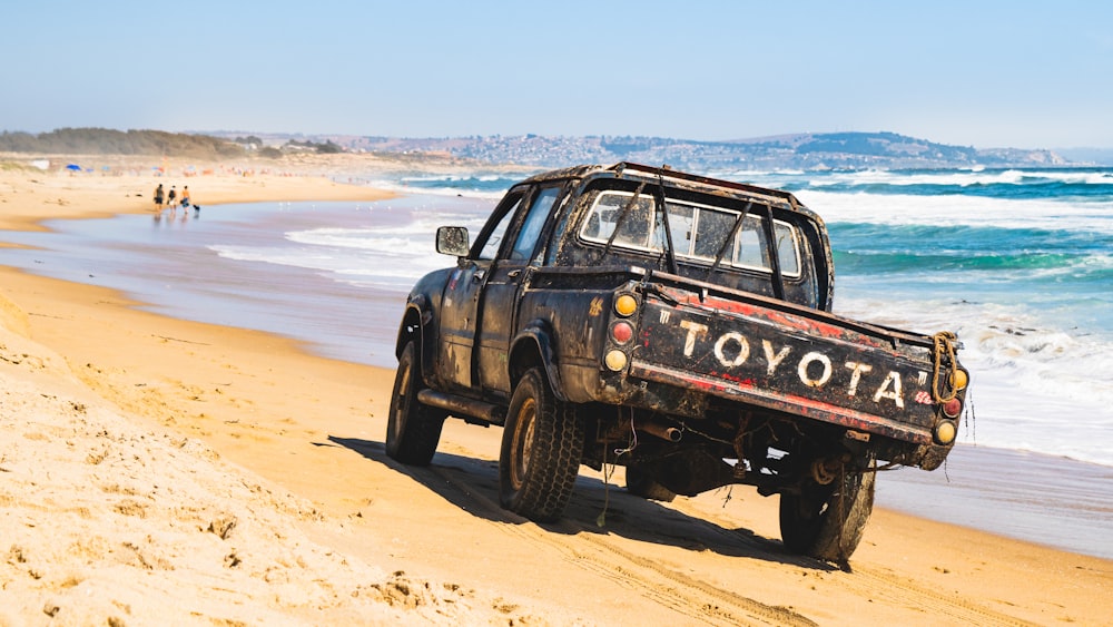 black suv on brown sand near body of water during daytime