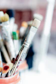 Close-up of a detailed ceramic brush holder filled with assorted paintbrushes.