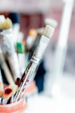 Close-up of a detailed ceramic brush holder filled with assorted paintbrushes.