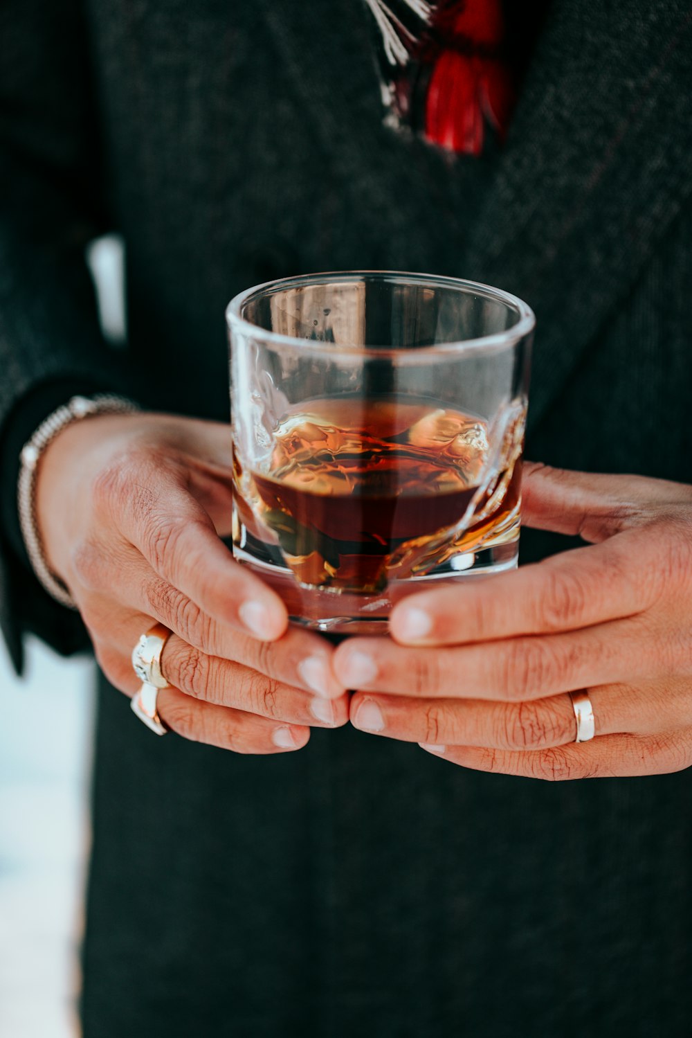 person holding clear drinking glass with red liquid