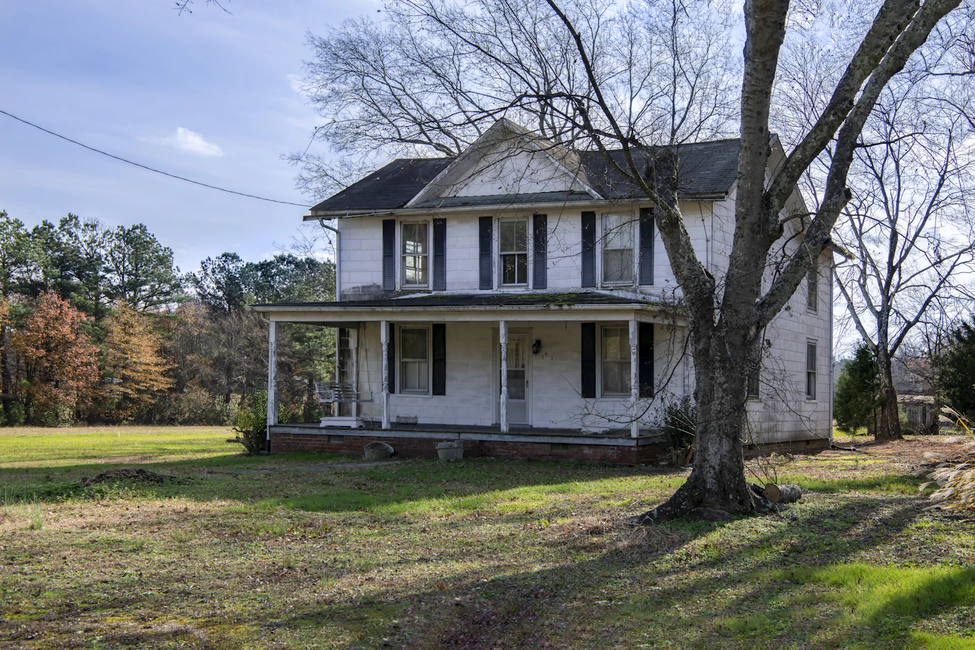 A white two-story farmhouse with a wide front porch