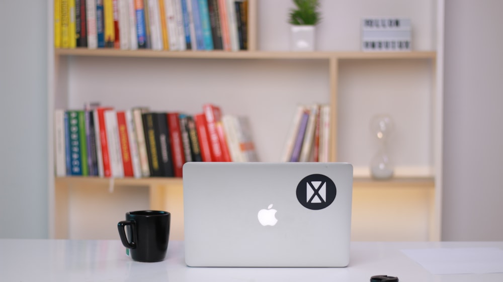 silver macbook on white table