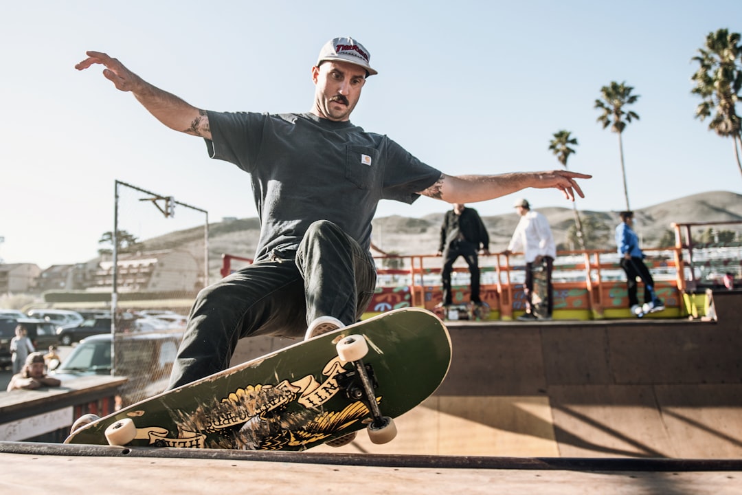 man in black crew neck t-shirt and black pants sitting on skateboard during daytime