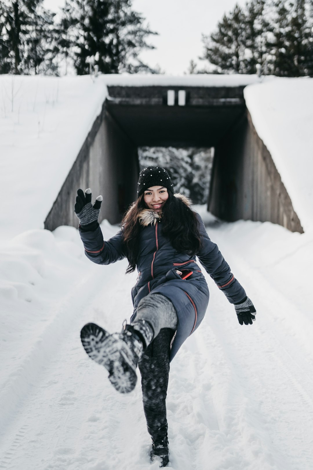 woman in black jacket and blue denim jeans lying on snow covered ground during daytime