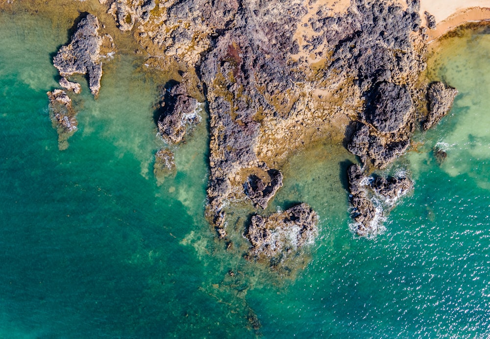 brown and black rock formation on body of water during daytime