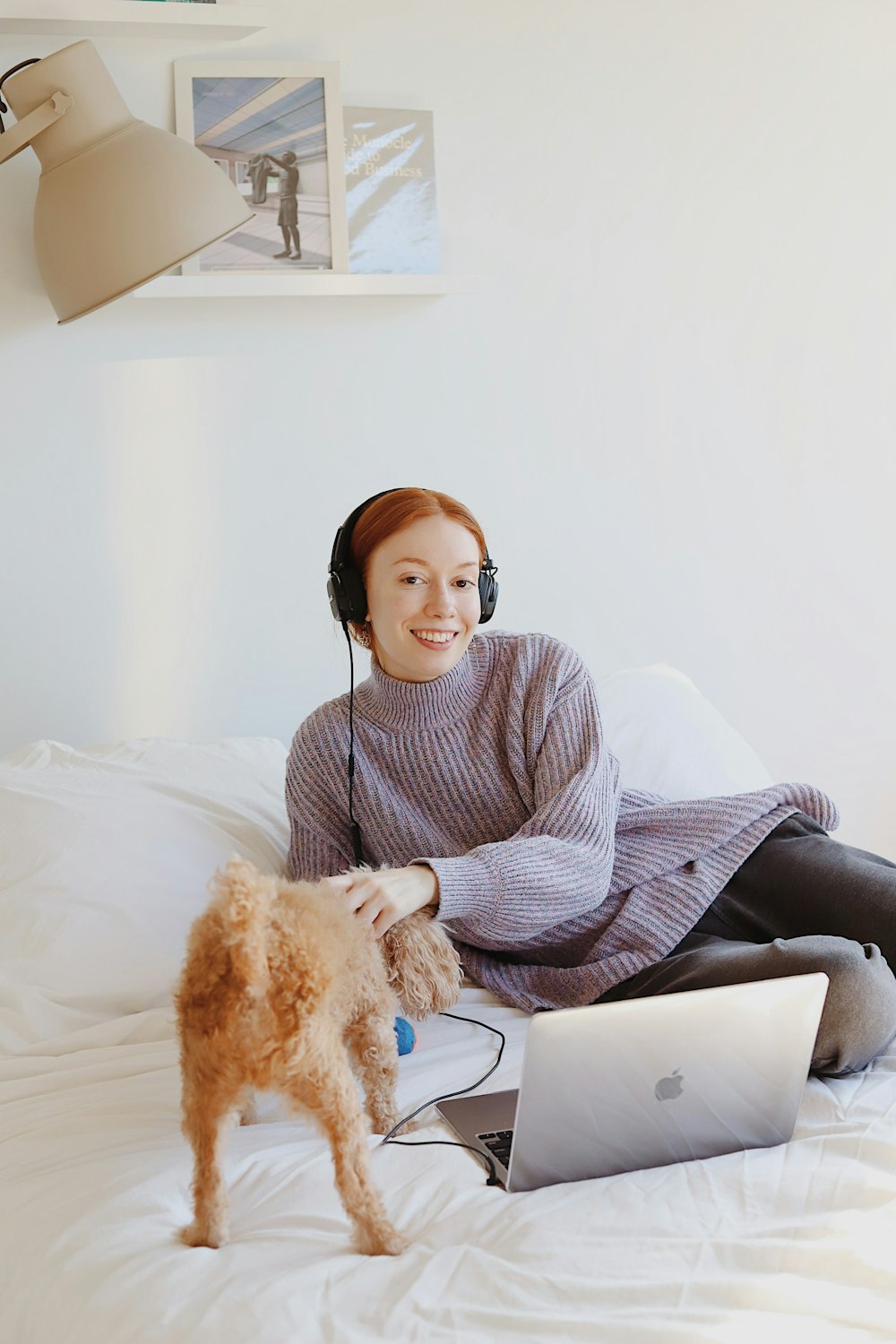 woman in gray and white striped long sleeve shirt and black pants sitting on white bed