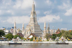 The Wat Arun temple with its central prang on the Chao Phraya river in Bangkok